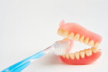 Dentures and toothbrush on a white background