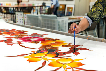 Painting with a brush on white silk fabric colour paints with cold batik style, Kuala Lumpur. Malaysia.