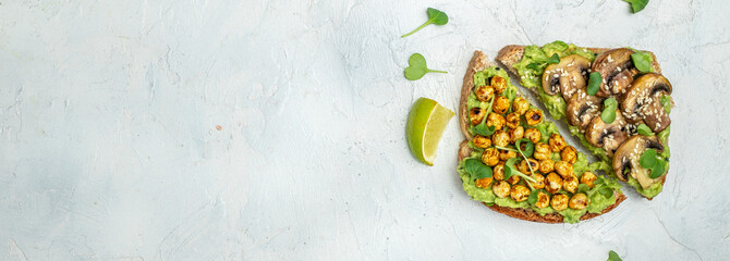 Healthy avocado toasts with chickpeas and mushrooms on a light background, vegetarian vegan food. Long banner format. top view