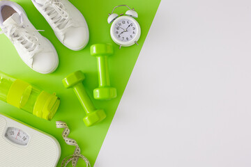 Fitness concept. Flat lay photo of dumbbells white sneakers bottle of water scales and alarm clock...