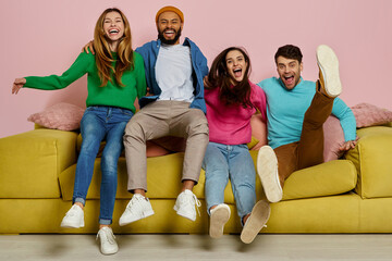 Studio shot of happy young people embracing and jumping on the couch together
