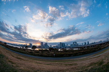 View of a park with buildings, a river and a bridge in the background during sunrise