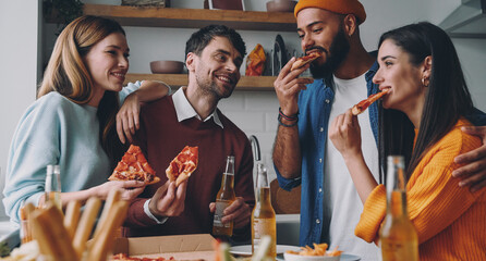Happy young people eating pizza and smiling while enjoying fun time together