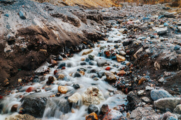A bubbling mountain stream. The flow of water among the rocks. A long exposure. mountain river close-up.