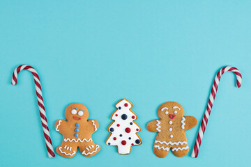 Delicious homemade ginger cookies in the form of men and a Christmas tree, Christmas sweets in the form of a cane on a blue background. Christmas background. Flat lay. Copy space.