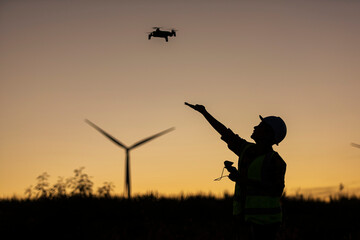 Fototapeta na wymiar silhouette of a person with UAV. Silhouette person take off UAV. on hand on wind turbine on background