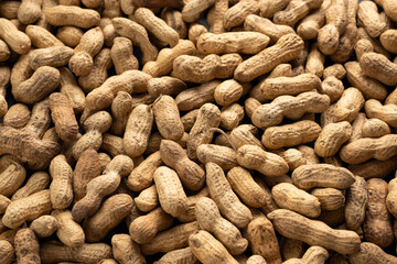 Background of dry unshelled peanuts, top view, close-up