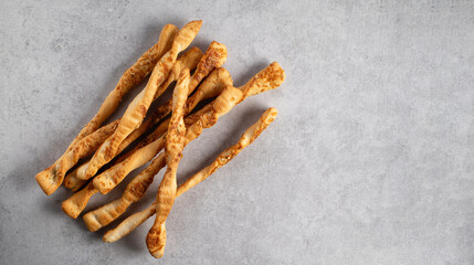 Grits, crispy bread sticks with parmesan cheese on gray stone background, banner, place for text, top view