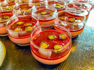 Panna cotta in milk with strawberry or raspberry sauce. Delicate Italian dessert, topped with natural jelly, decorated with halves of grapes. at catering event on some festive event, party or wedding