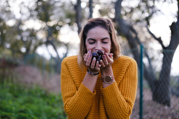 Young woman smelling freshly picked chestnuts during an autumn afternoon