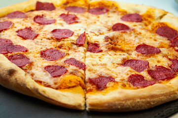 classic traditional dish pepperoni pizza with sausage Italian cuisine on a black background