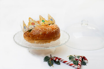 Roscon de reyes on a cake base with Christmas canes on a white background, typical dessert of Spain in January on Three Kings Day