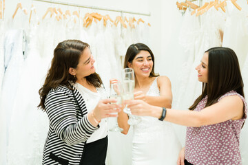 Cheerful latin women celebrating with champagne at the bridal store