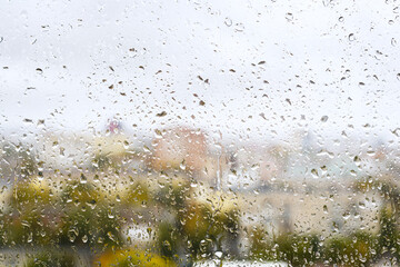 View of blurred city through the home window with raindrops