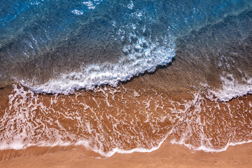 Turquoise water wave with sand beach background from aerial top view. Concept summer sunny travel image