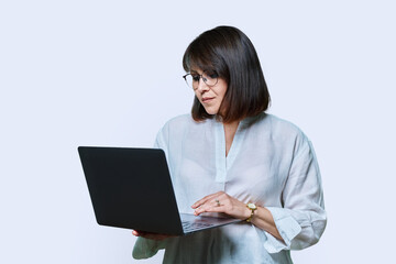Mature business woman using laptop on white studio background