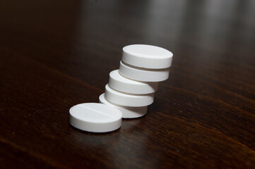 White round tablets on a wooden surface. A medicinal product.

