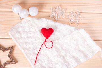 Red heart on a white knitted background with a fir twig. New Year's background