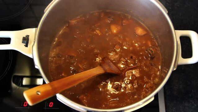Simmering cuttlefish, pasta in tomato sauce in a pot. Closeup