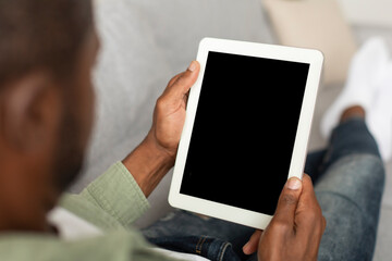 Middle aged black male looking at tablet with empty screen using new app for work and chat in...