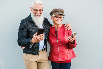 Senior couple having fun using mobile phones outdoor - Focus on faces