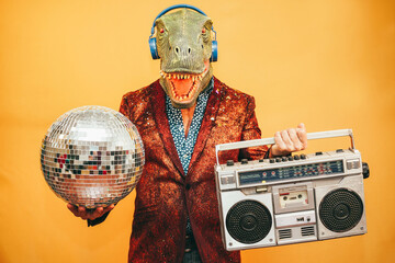 Crazy man wearing t-rex mask listening music with vintage boombox stereo during New year's eve - Focus on mask