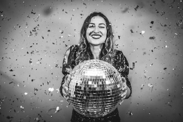 Happy fashion girl celebrating with disco ball and confetti during holiday party - Focus on face - Black and white editing