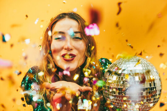 Happy girl blowing confetti holding vintage disco ball while celebrating new year's eve - Party concept - Focus on face