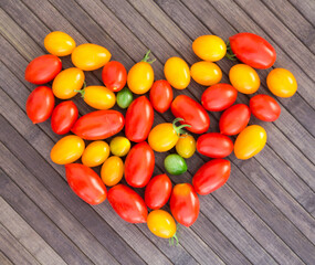 heart made of bright ripe yellow and red cherry tomatoes with place for inscription on wooden table