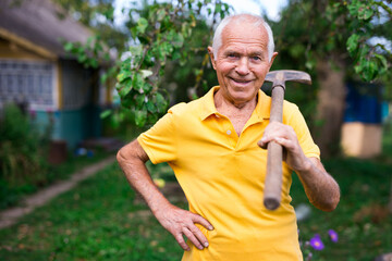 Naklejka na ściany i meble Portrait of an elderly man with shovel in garden