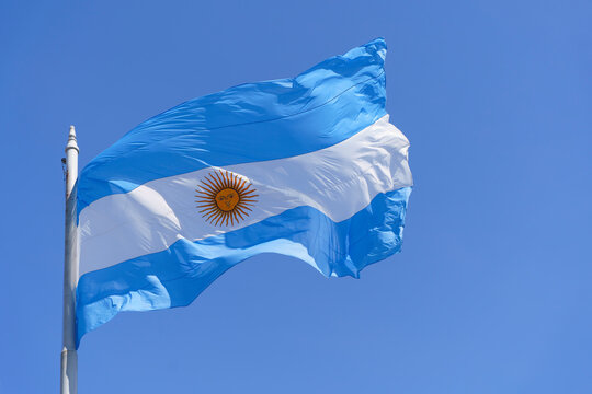 Argentinean flag on a clear blue sky background. Blue and white National symbol of Argentinean culture and patriotism.
