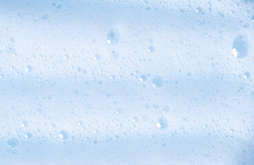 White foam texture with bubbles. Cosmetic soapy substance with bubbles. Creamy grainy macro backdrop. Cosmetic product foamy smudges and smears top view. White cleanser foam textured background.