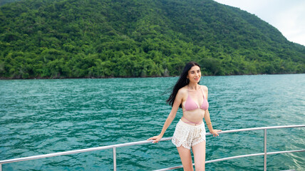 Portrait Attractive Happy beautiful sexy Asian female wearing swimwear enjoying on boat deck sailing luxury yacht. Vacation trip summer holiday.