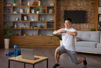 Sport and healthy lifestyle concept. Active asian man watching training tutorial on laptop and...