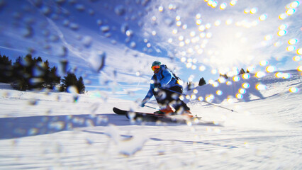 Professional skier skiing on slopes in the Swiss alps and throwing snow at the camera. Water drops visible.