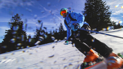 Professional skier skiing on slopes in the Swiss alps and throwing snow at the camera. Water drops...