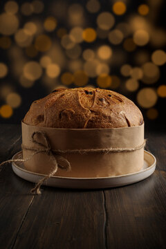Italian panettone. Traditional italian Christmas cake on wooden rustic background. Dark mood.