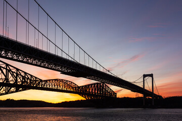 Low angle view of the 1970 suspension Pierre-Laporte Bridge and 1919 steel truss Quebec Bridge over the St. Lawrence River seen during sunrise, Quebec City, Quebec, Canada