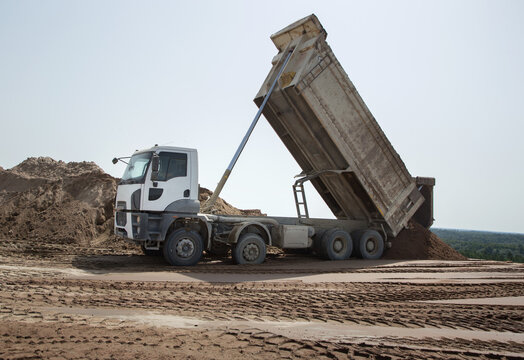 gray dump truck at the construction site in the process of transporting soil unloading. Excavation. Commercial vehicle for construction business