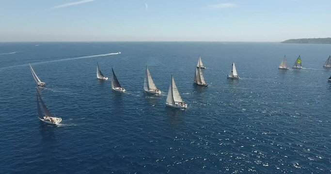 epic aerial view shots of the start of the Rolex Giraglia 2019 regatta, many sailing yachts have started and are making maneuvers dramatic sky