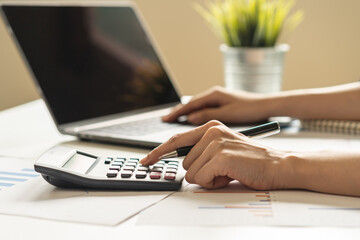 Account finance, asian young business woman hand using calculator, laptop computer for calculate budget, cost and income of company from paperwork, plan spend money expenses, working on desk at home.