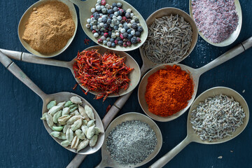 Set of spices in brass spoons, closeup, top view. Various peppers, cardamom, salt, paprika and saffron for cooking