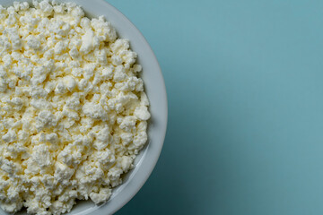 White cottage cheese in plate on blue background, top view, close up, copy space