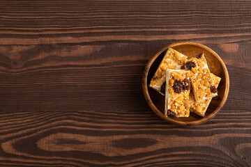 Obraz na płótnie Canvas Traditional candy nougat with nuts and sesame on brown wooden, top view, copy space.