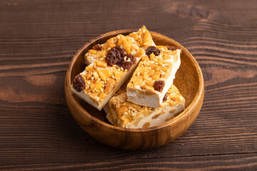 Traditional candy nougat with nuts and sesame on brown wooden, side view.