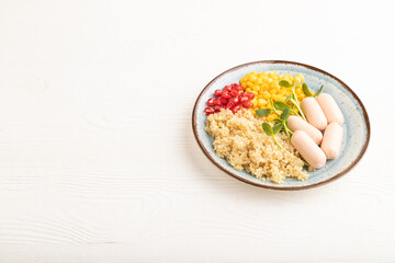 Mixed quinoa porridge, sweet corn and small sausages on white wooden, side view, copy space.
