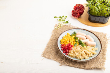 Mixed quinoa porridge, sweet corn and small sausages on white wooden, side view, copy space.