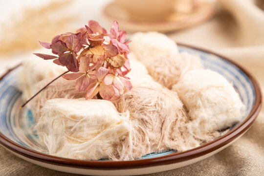 traditional arabic sweets pishmanie and a cup of green tea on white wooden,  side view, selective focus.
