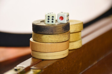 Wooden backgammon pieces stacked on top of each other on the backgammon board with game dice on them	