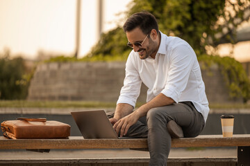 Handsome man working with laptop on city street